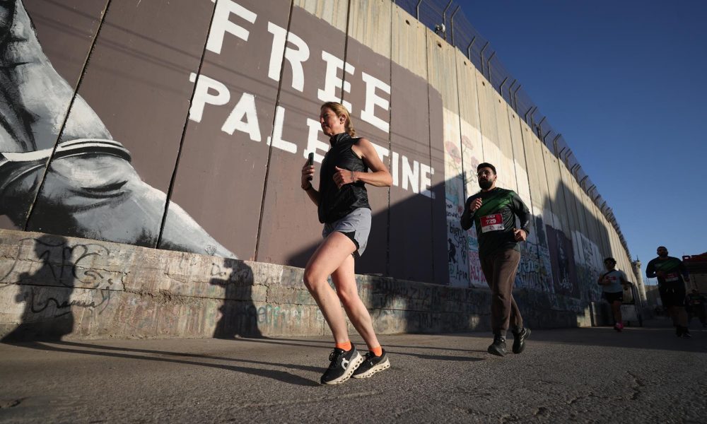 Belén (-), 08/05/2026.- Atletas palestinos e internacionales corren junto a grafitis en la barrera de separación israelí durante la décima Maratón Internacional de Palestina en la ciudad de Belén, en Cisjordania, el 8 de mayo de 2026. Según los organizadores, miles de corredores participaron en el evento, que incluyó una maratón completa, una media maratón y carreras de 10 y 5 kilómetros. (Maratón) EFE/EPA/ALAA BADARNEH