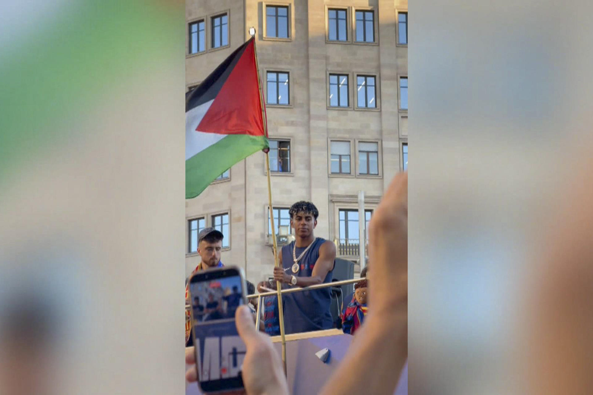 El delantero del Barcelona Lamine Yamal ondeó este lunes una bandera de Palestina durante la rúa de celebración del título de LaLiga, en la que unas 750.000 personas, según la Guardia Urbana, acompañaron al equipo azulgrana por las calles de la capital catalana. EFE/videoaficionada @Nuriacamera