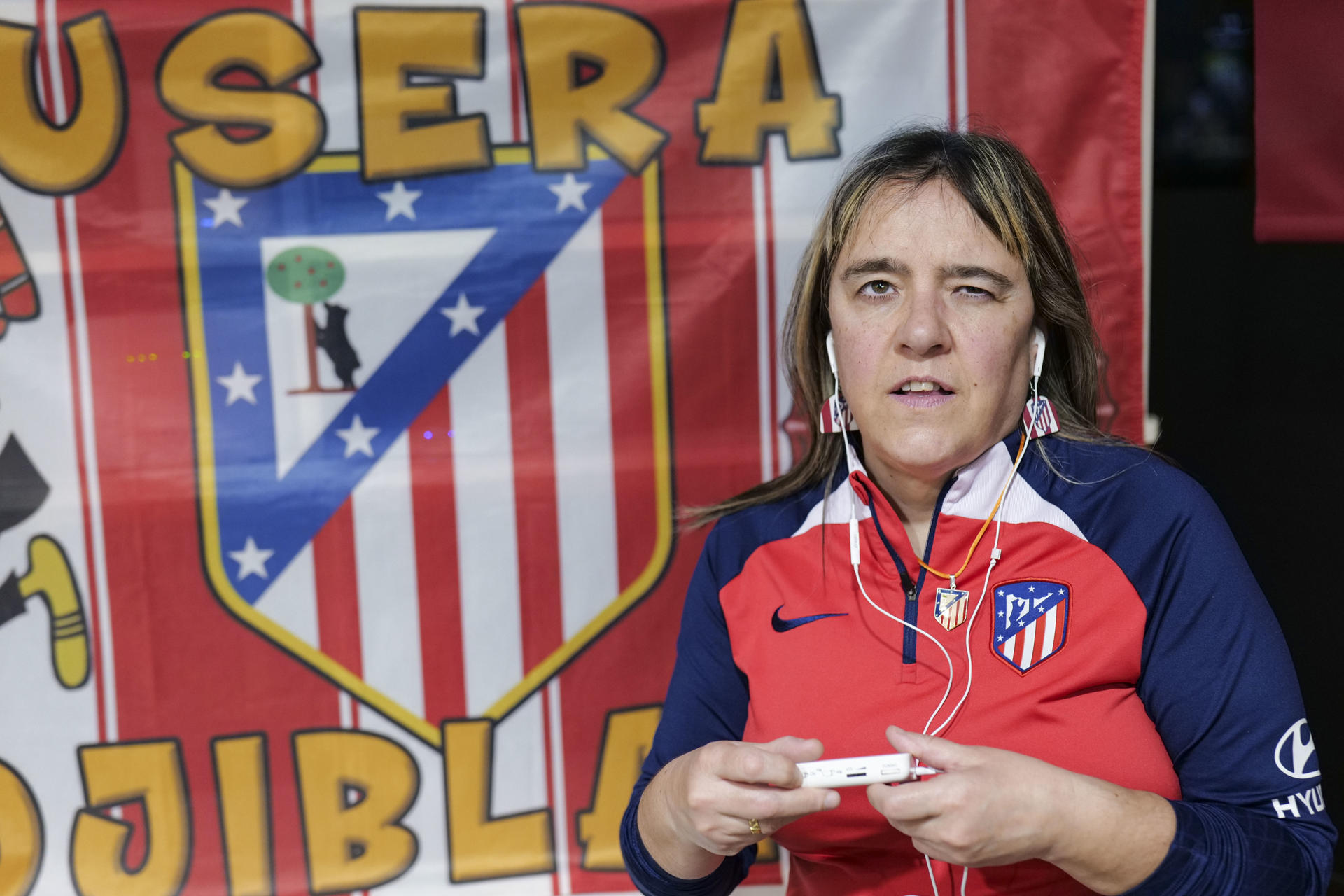 Cada fin de semana, los aficionados que van al estadio a animar a su equipo siguen el balón con la mirada, esperando que acabe en la portería contraria. En la primera fila del estadio Metropolitano hay una seguidora que vive los partidos del Atlético de Madrid de manera distinta, agarrada con fuerza a su radio analógica para no perderse el relato del partido, porque es ciega. Laura Cuervo Núñez (Madrid, 1973) cuenta que era rojiblanca antes de nacer, cuando su madre iba al estadio estando embarazada. De pequeña su padre la llevaba a ver todos los partidos, en una época en la que no era común ver a niñas en el estadio. Lo normal era ver a los padres con sus hijos, pero no con las hijas. No era como ahora, que las mujeres van al fútbol y juegan al fútbol, rememora a EFE con una sonrisa. EFE/Marc Fraile Baudy
