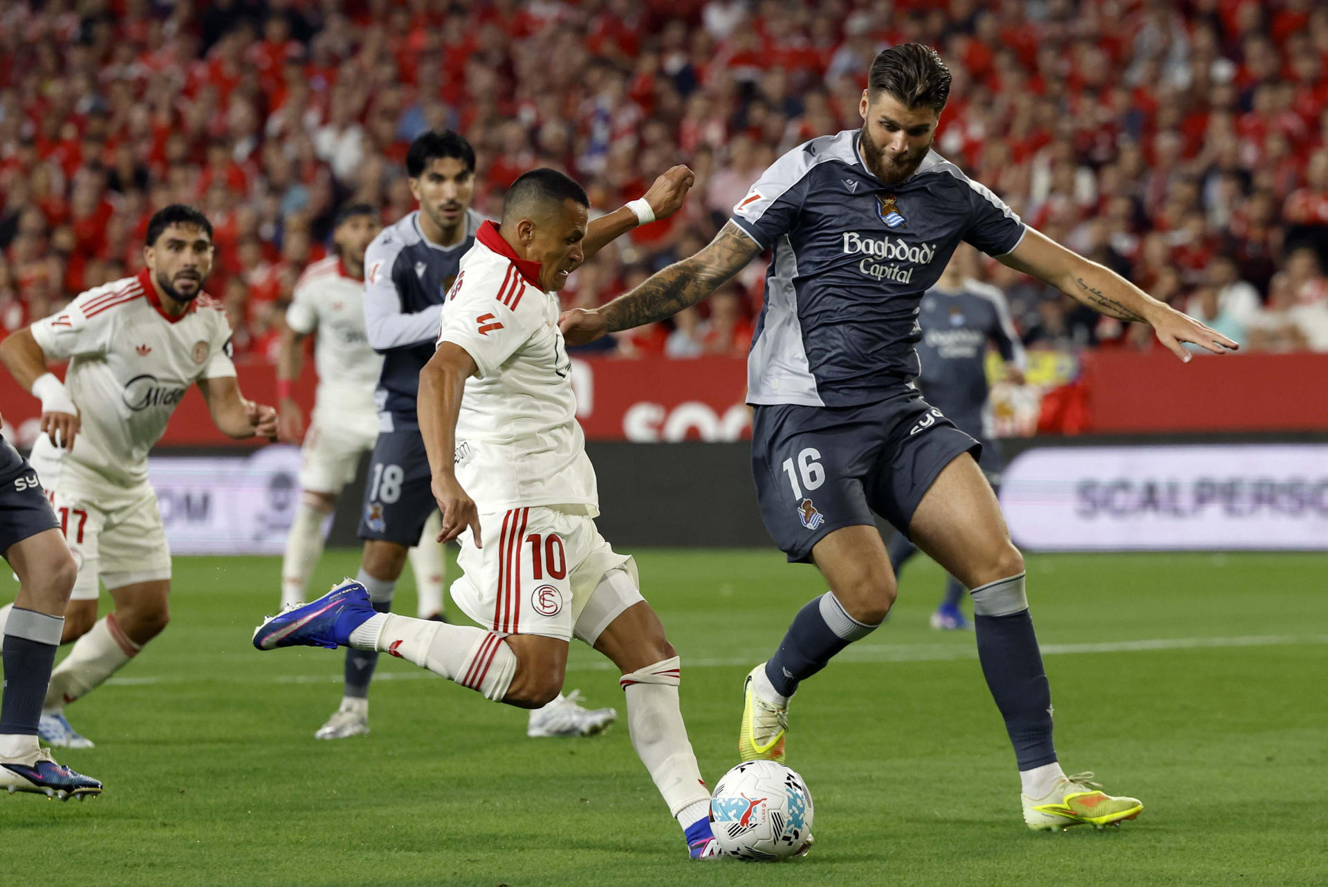 El defensa de la Real Sociedad Duje Ćaleta-Carbalón (d) disputa un balón ante el delantero del Sevilla Alexis Sánchez (i) durante el partido de la jornada 34 de LaLiga EA Sports que el Sevilla FC y la Real Sociedad disputaron en el estadio Ramón Sánchez-Pizjuán de la capital andaluza. EFE/ Julio Muñoz