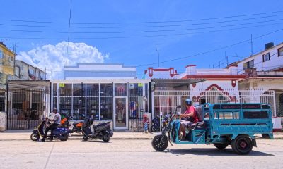 Personas transitan en motos eléctricas frente a un mercado privado este martes, en La Habana (Cuba). EFE/ Ernesto Mastrascusa
