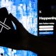 Imagen de archivo del 27 de julio de 2022, en la que puede verse a un usuario mientras sostiene un teléfono móvil que muestra el logotipo de la red social X. EFE/Etienne Laurent