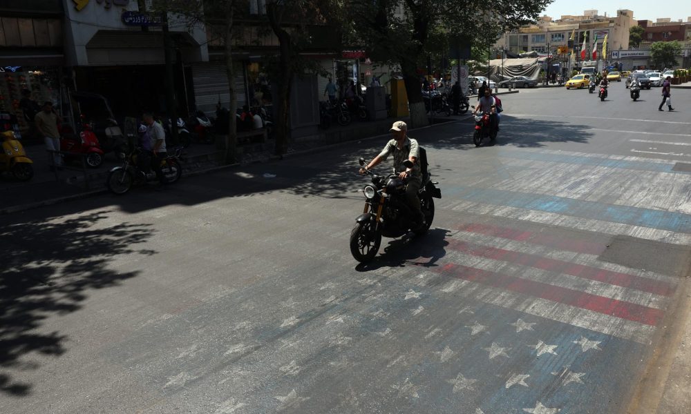 Una motocicleta pasa por encima de una bandera estadounidense pintada en una calle de Teherán, Irán, este miércoles 10 de junio de 2026. Según el Comando Central de EE. UU. (CENTCOM), se llevaron a cabo ataques contra Irán cerca del Estrecho de Ormuz el 9 de junio en respuesta al derribo de un helicóptero Apache del Ejército de EE. UU. (Teherán) EFE/EPA/ABEDIN TAHERKENAREH RESTRICCIONES: SIN Acceso Medios de Israel/Cadenas de Televisión en Idioma Persa Fuera de Irán/Estrictamente SIN Acceso BBC Persa/VOA Persa/Manoto TV/Iran International TV. (Según lo ordenado por la Dirección General de Medios Extranjeros de Irán) --