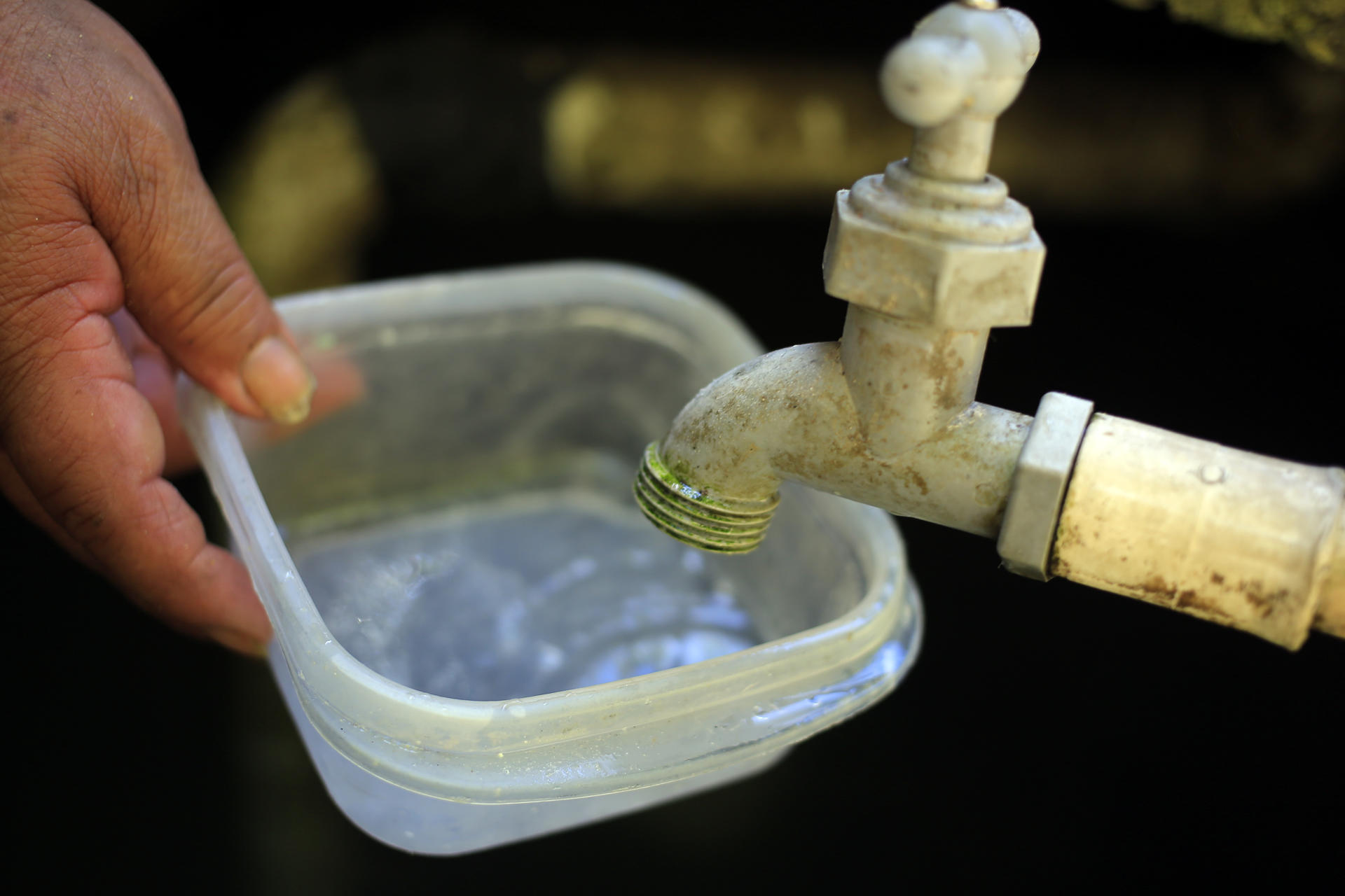 Fotografía de archivo donde se observa a una persona mientras intenta llenar un recipiente con agua. EFE/ Gustavo Amador