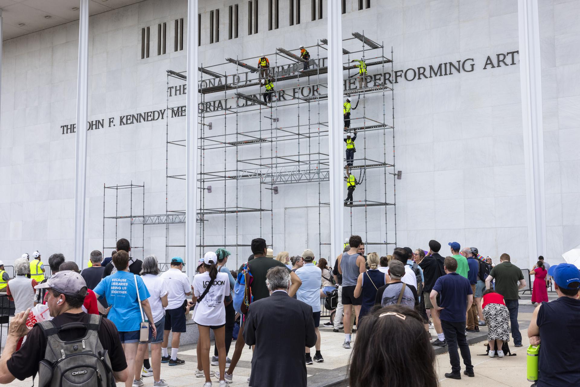 Los espectadores observan cómo los trabajadores se preparan para retirar el nombre del presidente estadounidense, Donald J. Trump, de la fachada del Centro John F. Kennedy para las Artes Escénicas en Washington, DC, EE. UU., el 12 de junio de 2026. EFE/EPA/JIM LO SCALZO