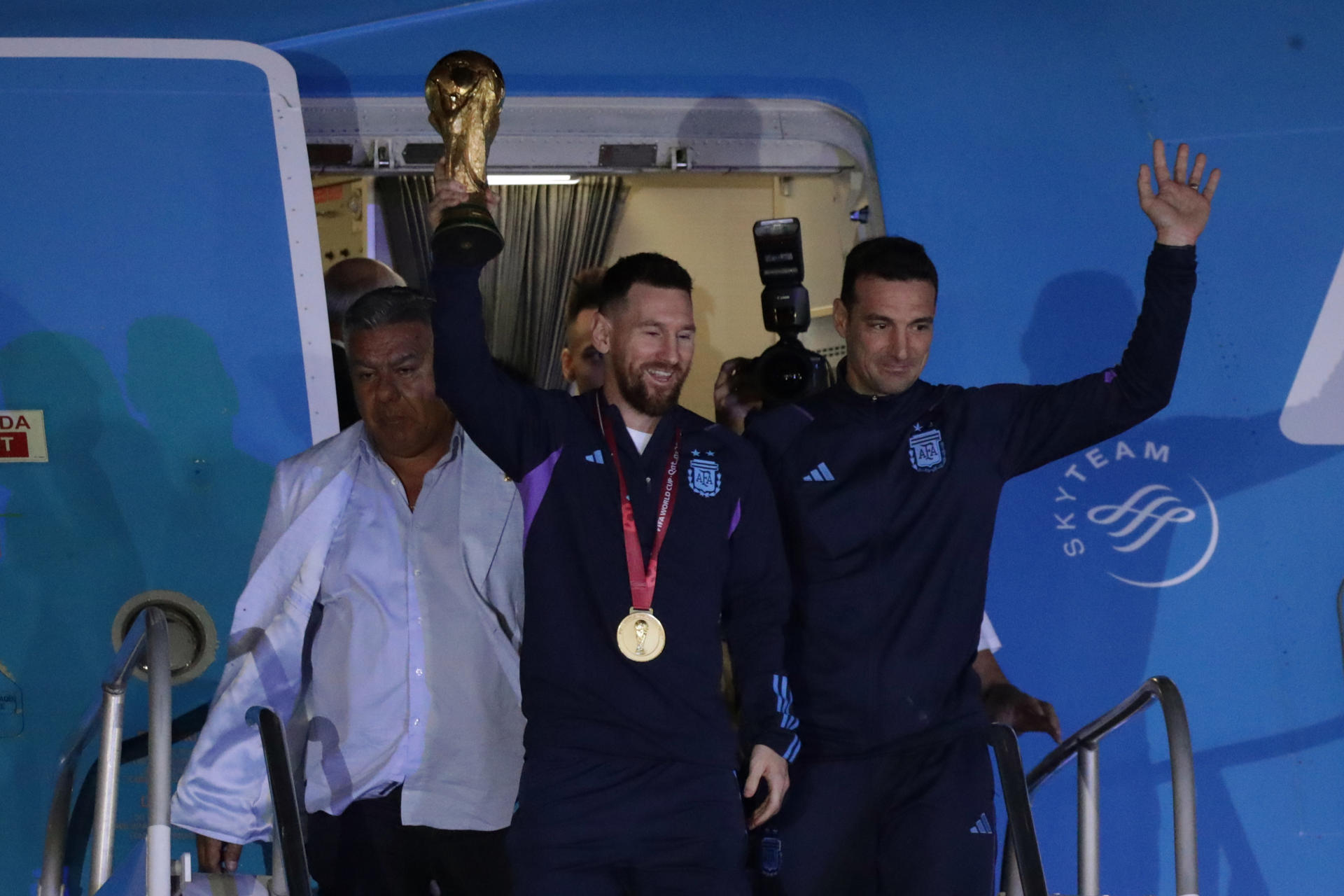 Lionel Messi saluda con el trofeo del Mundial de Fútbol Qatar 2022 junto al seleccionador Lionel Scaloni (d) a su llegada al Aeropuerto Internacional de Ezeiza, tras conquistar la Copa del Mundo 2022. EFE/ Raúl Martínez