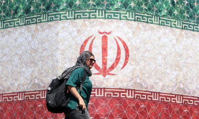 Una mujer iraní pasa junto a una valla publicitaria con la bandera nacional de Irán en la plaza Enqelab de Teherán, Irán. EFE/EPA/ABEDIN TAHERKENAREH. RESTRICCIONES: Prohibido el acceso a medios de comunicación israelíes/canales de televisión en persa fuera de Irán/Prohibido el acceso a BBC Persian/VOA Persian/Manoto TV/Televisión Internacional de Irán. (Según lo dispuesto por la Dirección General de Medios de Comunicación Extranjeros de Irán).
